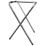 A folding metal luggage rack with chrome plated, tubular construction features crossed legs and black straps forming a flat surface at the top. Its minimalist design includes small black caps on each leg for added stability.