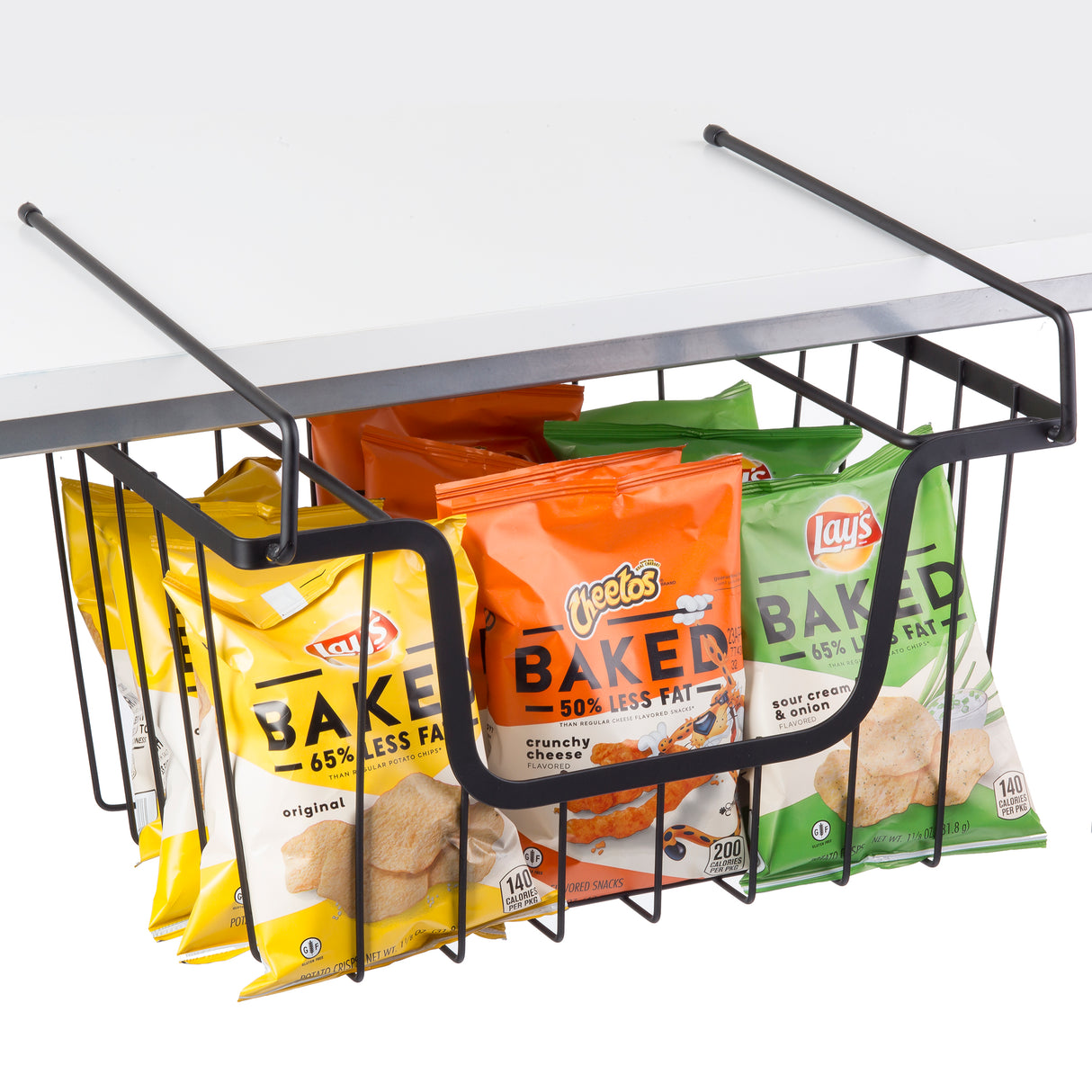 A black powder coated metal basket hangs from a white shelf, holding multiple bags of Lay’s and Cheetos Baked chips. The stackable hanging basket keeps snack storage organized with colorful bags showing BAKED and 65% less fat.