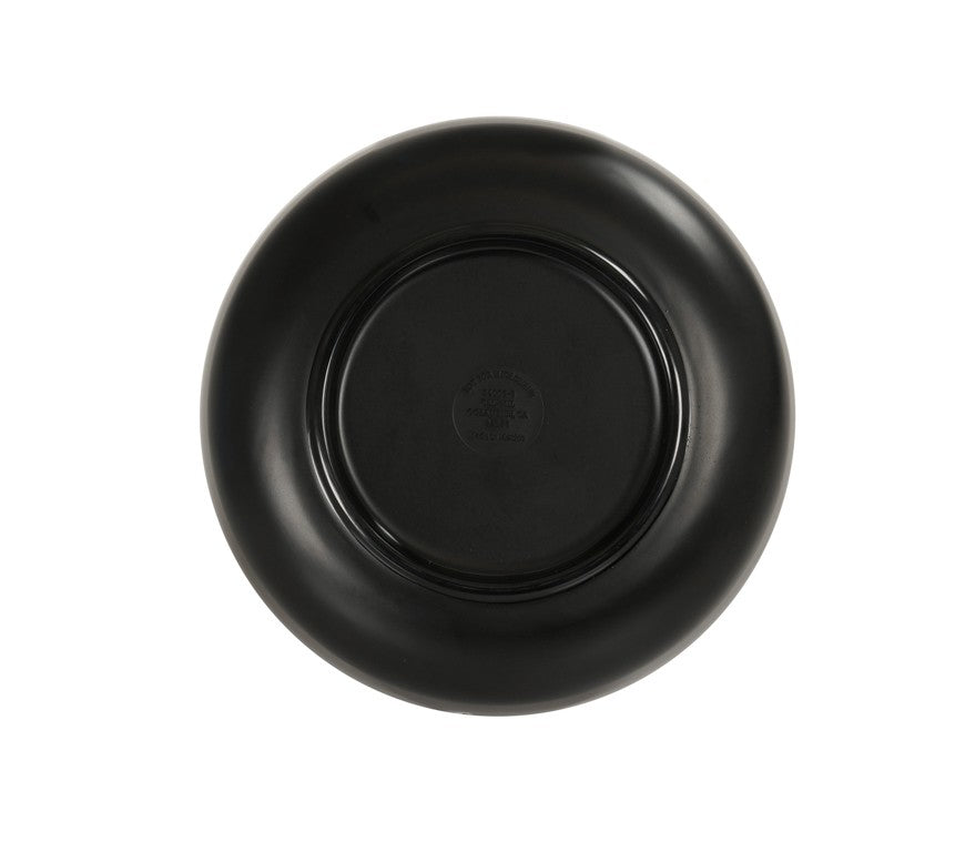 A black ceramic plate is shown from above, displaying its underside. The plate, reminiscent of an Oslo Bowl, has a glossy finish and a slightly raised base. There is a faint, circular maker’s mark with text and a logo in the center of the base.