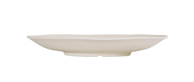 A white, shallow, oval-shaped ceramic plate with slightly wavy edges is shown in profile against a plain white background. Dishwasher safe, it features a smooth surface and sits on a small, rounded base for added elegance.
