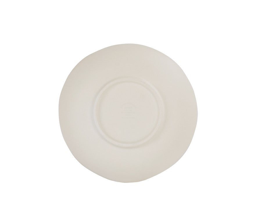 A plain, white ceramic plate lies upside down against a white background. The plate has a slightly irregular, organic shape, reminiscent of a hand thrown bowl. Subtle embossed text is visible on the underside but is not clearly readable.