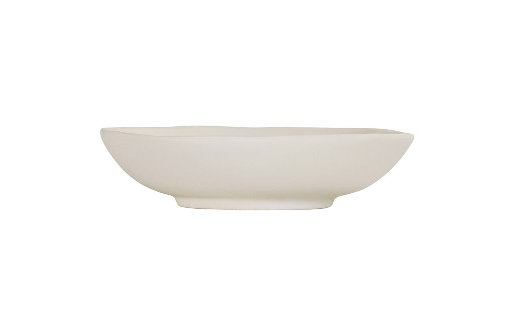 A plain, white, hand thrown bowl with smooth, gently curved sides and a slightly uneven rim sits on a white background. The minimalist, unadorned design gives this ceramic vessel a simple and modern appearance.