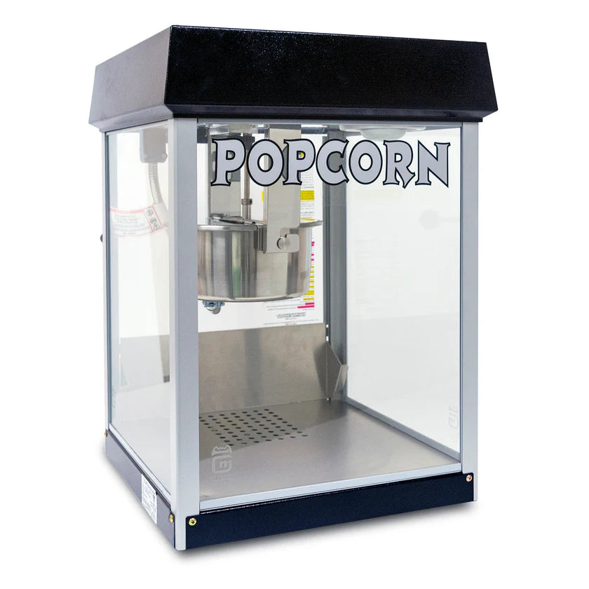 A countertop popcorn machine with a black top, clear glass sides, and the word POPCORN in bold letters on the front. The metal popping kettle of this 4 oz popcorn maker is visible above a perforated metal tray at the bottom.
