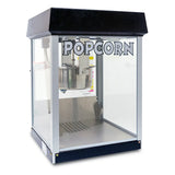 A countertop popcorn machine with a black top, clear glass sides, and the word POPCORN in bold letters on the front. The metal popping kettle of this 4 oz popcorn maker is visible above a perforated metal tray at the bottom.