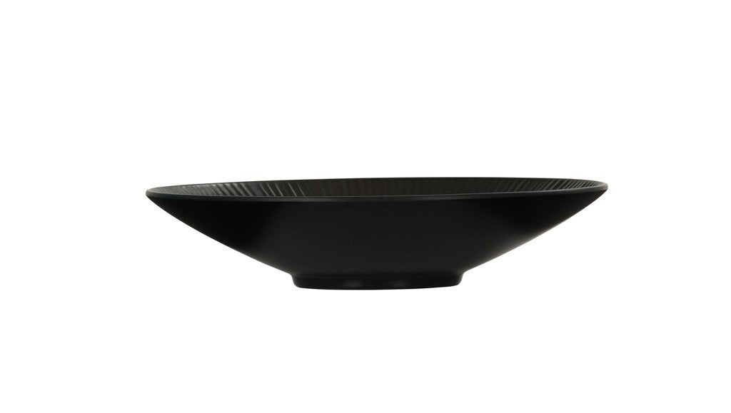 A shallow, wide-rimmed Nomi Bowl with a smooth matte finish, viewed from the side against a plain white background. This melamine bowl features a slightly flared rim, a small circular base, and is dishwasher safe for easy cleaning.