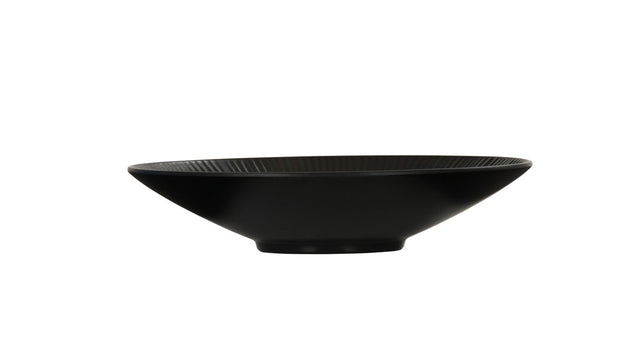 A shallow, wide-rimmed Nomi Bowl with a smooth matte finish, viewed from the side against a plain white background. This melamine bowl features a slightly flared rim, a small circular base, and is dishwasher safe for easy cleaning.