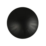 A round, matte black melamine plate viewed from above, featuring a subtle radial pattern of ridges radiating to the edges for a sunburst effect. This dishwasher safe design pops against the plain white background.