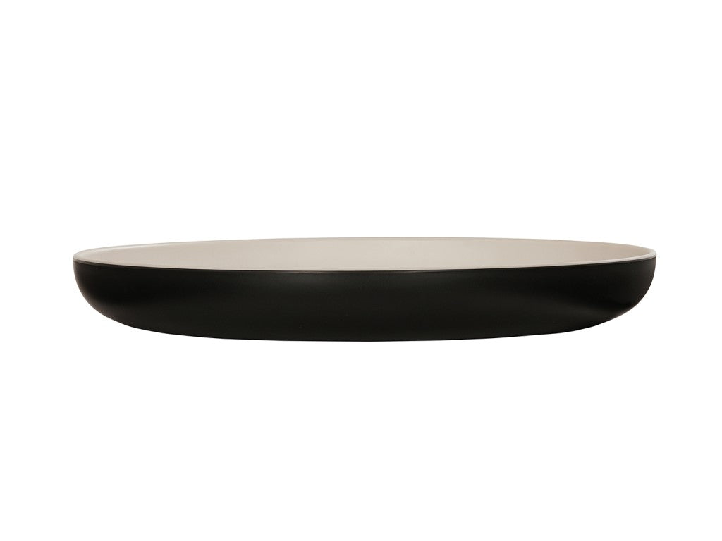 A shallow, round two-tone pasta bowl with a smooth, matte black exterior and a glossy white interior, shown from the side against a white background. The dish has gently curved sides and a flat base.