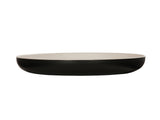A shallow, round two-tone pasta bowl with a smooth, matte black exterior and a glossy white interior, shown from the side against a white background. The dish has gently curved sides and a flat base.