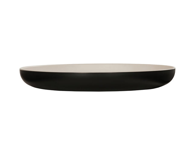 A shallow, round two-tone pasta bowl with a smooth, matte black exterior and a glossy white interior, shown from the side against a white background. The dish has gently curved sides and a flat base.
