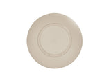 A beige, round ceramic plate, reminiscent of the Charlotte Bowl, is shown from above. It features a simple design with concentric ridges along the outer rim and a smooth, slightly recessed center. The background is plain white.