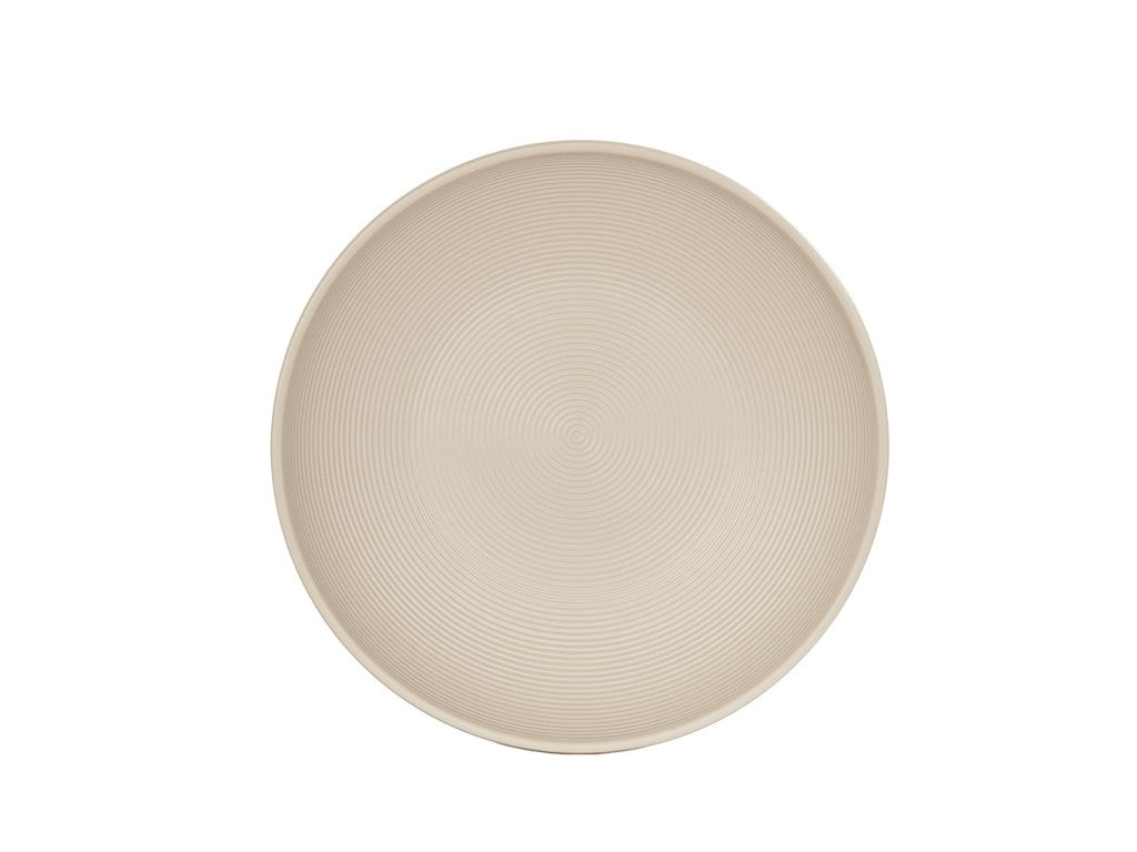 A round, beige dinner plate with a subtle concentric circle pattern is centered on a plain white background. The smooth, slightly raised rim echoes the minimalist, modern style of the Charlotte Bowl collection.