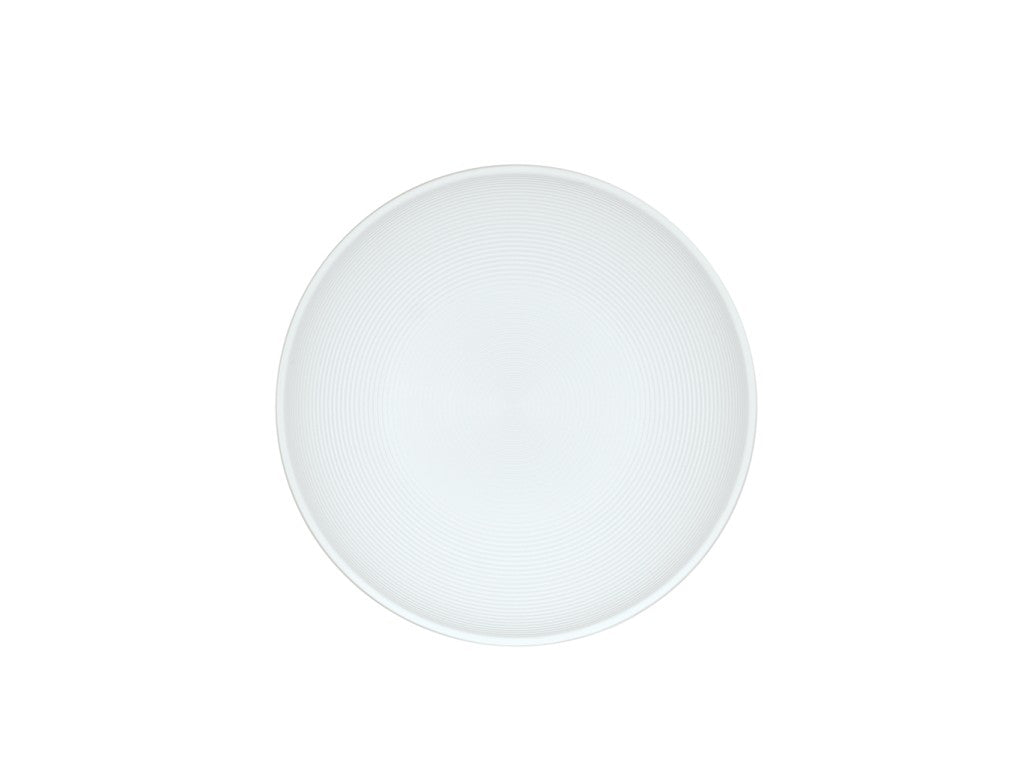 A plain, round white ceramic plate viewed from above, centered on a white background. Reminiscent of a Charlotte Bowl, it features subtle concentric circular ridges and no patterns or decorations.