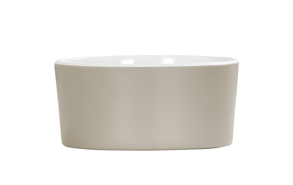 A plain, round, light beige ceramic bowl with smooth sides and a glossy white interior, shown against a white background. Minimalistic and unadorned, this dishwasher safe design is ideal for serving food or as a decorative piece.