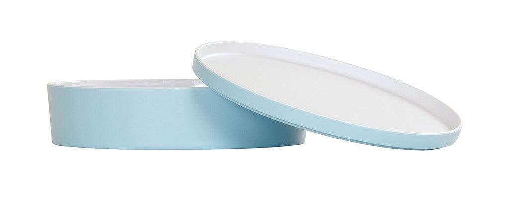 A round, shallow, light blue melamine container with a matching lid. The bento box is positioned flat, while the lid is propped at an angle. Both pieces have white interiors and are dishwasher safe, shown on a plain white background.