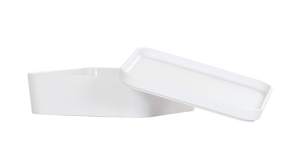 A white, geometric, asymmetrical Bento Box made of smooth melamine features a matching flat lid resting partly askew. The plain white background highlights its modern, minimalist design—and it’s dishwasher safe for easy cleaning.
