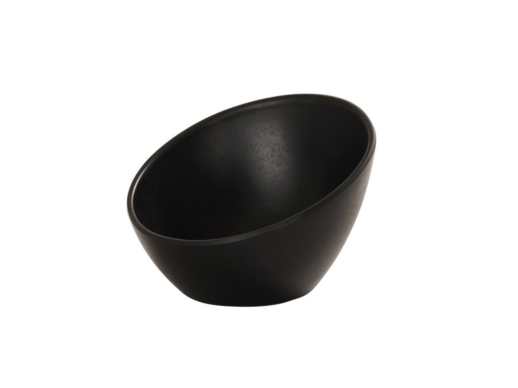 A matte black bowl with a slanted rim sits on a white background. This 5 inch round bowl features a smooth, modern surface and minimalist design, with the opening tilted at an angle for a unique, contemporary look.