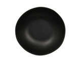 A round, matte black ceramic plate viewed from above. Reminiscent of a Bali Pasta Bowl, it has a smooth, slightly curved surface and subtle, uneven rim for a modern, minimalist look. The background is plain and white.