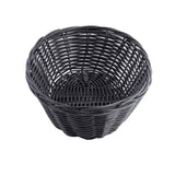 A round, empty, black hand-woven basket with a wide opening and woven pattern, set against a white background. The basket’s curved sides and interlaced texture are clearly visible.