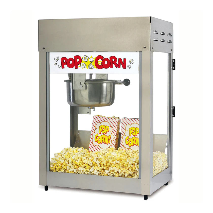 A countertop popcorn machine with a stainless steel kettle brims with popcorn. Two red and yellow striped popcorn bags labeled Pop Corn rest inside, beneath a sign reading “POP CORN” in bold red letters with cartoon popcorn graphics.
