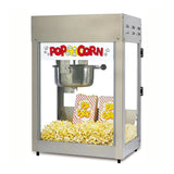 A countertop popcorn machine with a stainless steel kettle brims with popcorn. Two red and yellow striped popcorn bags labeled Pop Corn rest inside, beneath a sign reading “POP CORN” in bold red letters with cartoon popcorn graphics.