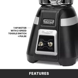 Close-up of a black Waring Commercial bar blender base, with silver toggle switches labeled “High,” “Low,” “Off,” and “Pulse.” Text beside it reads: “1 HP motor with 2-speed toggle switch + pulse.” The word “Features” appears at the bottom.
