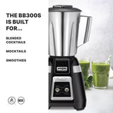 A stainless steel Waring Commercial bar blender sits on a counter next to two glasses filled with green smoothies and leafy greens. Text on the left reads: THE BB300S IS BUILT FOR... BLENDED COCKTAILS, MOCKTAILS, SMOOTHIES. NSF and certification icons are below.