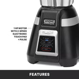 Close-up of a black Waring bar blender base featuring a control panel with ON/OFF, LOW, HIGH, PULSE, and STOP buttons. Text highlights the powerful 1 HP motor with 2-speed electronic touch pad + pulse. "FEATURES" appears at the bottom.