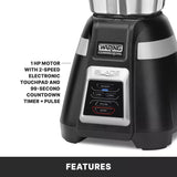 Close-up of a black Waring Commercial bar blender base with a silver touchpad. Panel features ON/OFF, LOW, HIGH, PULSE, and STOP buttons. Text: 1 HP motor with 2-speed electronic touchpad and 99-second countdown timer + pulse.