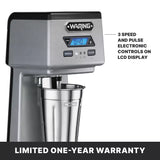 A silver Waring WDM120TX single spindle Drink Mixer with a digital LCD showing 0:40, labeled speed and pulse controls, and a metal mixing cup. Text highlights “3 speed and pulse electronic controls.” Black bar notes “Limited one-year warranty.”.