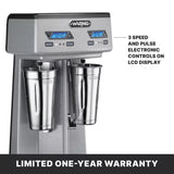 A silver Waring double spindle drink mixer with two metal cups and blue LCD displays. Buttons for speed and pulse are visible. Text highlights 3 speed and pulse electronic controls on the screen. Banner at the bottom reads, Limited one-year warranty.
