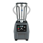 A commercial blender with a metal base, digital control panel, and two side handles. It features a large stainless steel container, clear lid, and front buttons and dial marked CB15 and Waring Commercial for precise variable speed control.