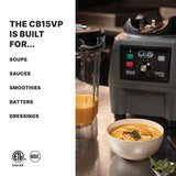 A heavy-duty food blender labeled CB15 The Legend sits on a stainless steel surface beside its pitcher filled with orange soup. In front, a bowl of orange soup is garnished with herbs. Perfect as a 1 gallon blender for soups, sauces, smoothies, and more.