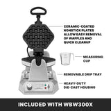 A silver bubble waffle maker with honeycomb-patterned non-stick plates is open. Labeled features include non-stick plates, a measuring cup, removable drip tray, and heavy-duty die cast housing. Text below reads “Included with WBW300X.”.