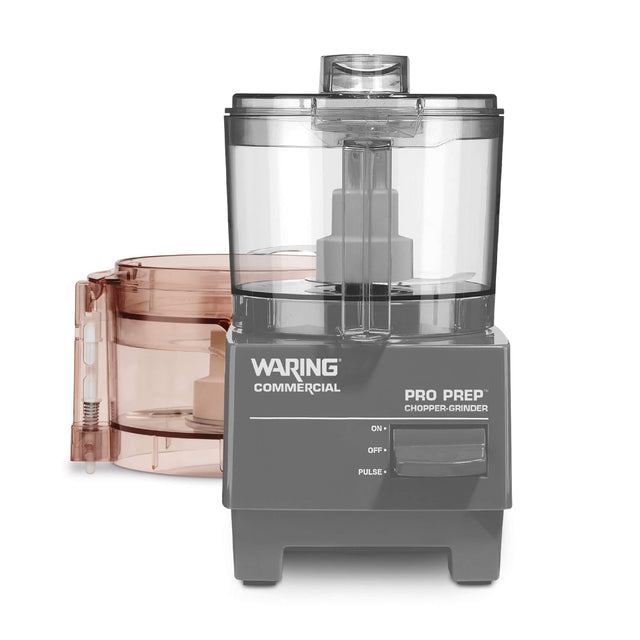 A gray Waring Commercial Pro Prep Chopper Grinder with a clear plastic lid and base, featuring a 3 cup capacity. The device has an on/off/pulse switch, and comes with an extra bowl with lid, both containing white chopping blades inside.