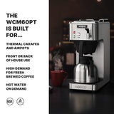 A thermal coffee brewer sits on a dark counter, brewing coffee into a metal carafe. A red mug, silver spoon, and steaming cup evoke café deco vibes. Bold text highlights this commercial coffee maker’s hot water on demand and fresh brewed features.