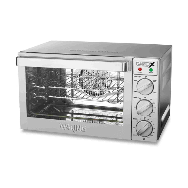 A stainless steel Waring WCO250X countertop oven with a glass front door, three control knobs for function, temperature, and timer, indicator lights, two wire racks, and a baking tray. The brand “Waring” is embossed on the front panel.