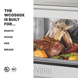 A close-up of a stainless steel commercial convection oven with a cooked rack of lamb on vegetables inside. On the left, bold text reads “The WCO500X is built for… Roasts, Pizzas, Pies, Breads.” UL and NSF certification logos appear at the bottom.