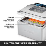 A Waring Vacuum Packaging Machine with its lid open sits on a countertop, sealing vacuum bags filled with orange items. Labels highlight the 2-gallon stainless steel chamber and 11-inch seal bar. Text below reads: LIMITED ONE-YEAR WARRANTY.