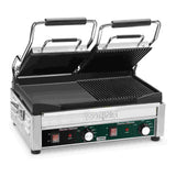 A stainless steel Waring Dual Surface Panini Grill features two hinged, ribbed grill plates—one open and one partially closed. The front panel includes adjustable thermostats, indicator lights, switches, and the Panini Ottimo label.