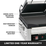 A stainless steel Commercial Panini Grill with a hinged top plate, adjustable thermostats, heat-resistant handles, and adjustable back feet. The open top reveals the dual surface grill. A label at the bottom reads LIMITED ONE-YEAR WARRANTY in bold white text.