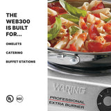 A stainless steel Waring professional extra burner with a cast iron burner supports a pot of penne pasta topped with tomato sauce and basil. Text on the left reads: “THE WEB300 IS BUILT FOR… omelets, catering, buffet stations.” UL and NSF logos appear below.