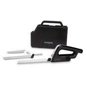 A black and silver electric carving knife set with two serrated blades, a carving fork, and a black carrying case labeled Waring. The knife handle and blades are arranged in front of the closed case on a white background.
