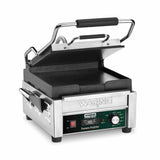 A compact toasting grill, this stainless steel Waring commercial sandwich press features flat cast iron plates, a black handle, control panel with green and red lights, adjustable thermostats, and "Tostato Perfetto" labeling.