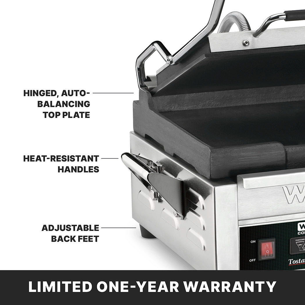 A close-up of a stainless steel panini press with its lid partially open. Labeled features include flat cast iron plates, a hinged auto-balancing top plate, heat-resistant handles, and adjustable back feet. “LIMITED ONE-YEAR WARRANTY” appears at the bottom.