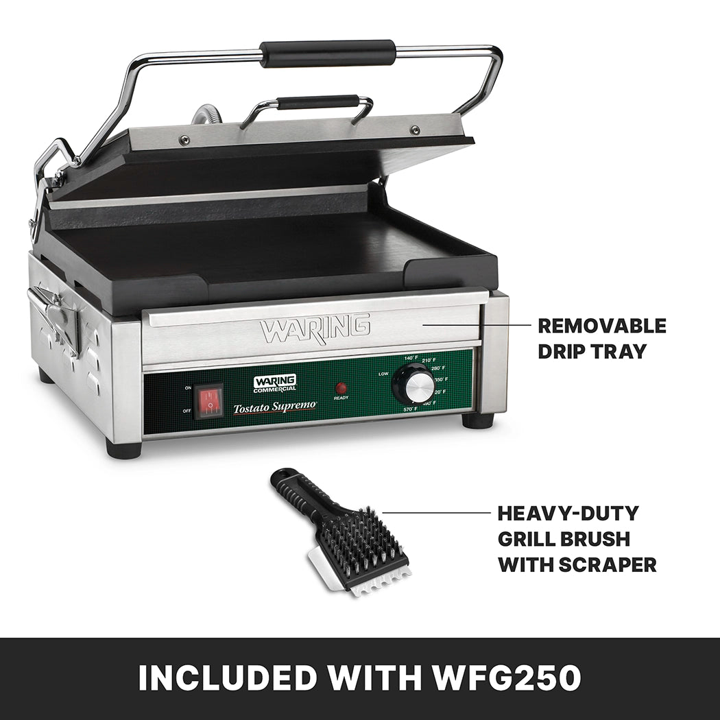 A stainless steel Waring panini press sits open, showing flat cast iron plates. The control panel has a green dial and switches for adjustable thermostats. Text points to a removable drip tray and heavy-duty grill brush with scraper, both included with model WFG250.