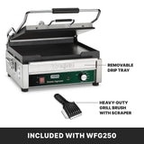 A stainless steel Waring panini press sits open, showing flat cast iron plates. The control panel has a green dial and switches for adjustable thermostats. Text points to a removable drip tray and heavy-duty grill brush with scraper, both included with model WFG250.