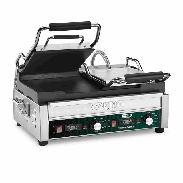 A stainless steel commercial dual toasting grill with black handles and adjustable knobs on the front panel, labeled “Waring” and “Toastie Ottimo.” The grill plates are partially open, revealing flat cast iron plates for even cooking.