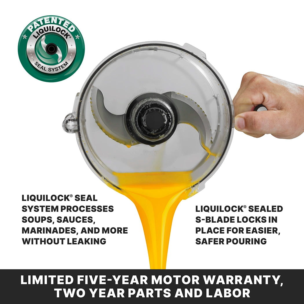 A clear Commercial batch bowl food processor with a metal S-blade has yellow liquid pouring smoothly, thanks to the LiquiLock seal system. The Waring WFP14SE also features a limited five-year motor warranty.