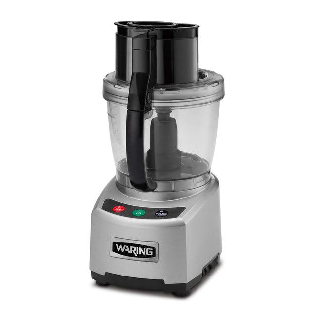 A silver Waring food processor with a clear 4 qt batch bowl and black handle. The base features three buttons: green, red, and black, with icons and text. The lid has a feed tube, pusher, and LiquiLock seal system. Waring logo on the front.